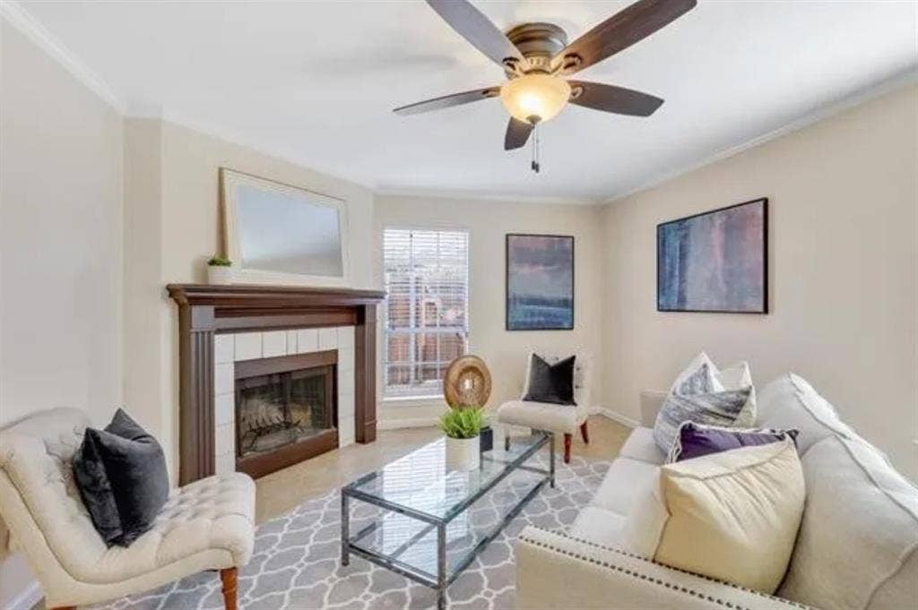 8400 Hickory Street, #1504, Frisco, TX 75034 Living area featuring a fireplace with a wood mantle and tile surround, ceiling fan with integrated lighting, and crown molding
