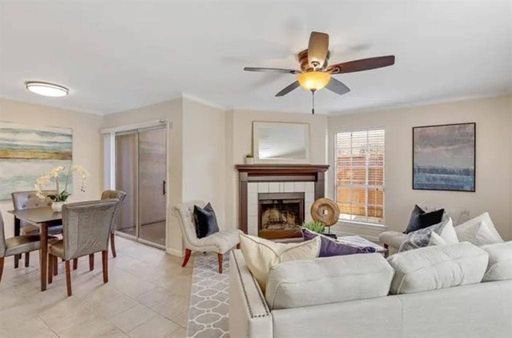 8400 Hickory Street, #1504, Frisco, TX 75034 Living room featuring a wood-mantled fireplace with tile surround, ceiling fan with integrated lighting, and neutral wall tones