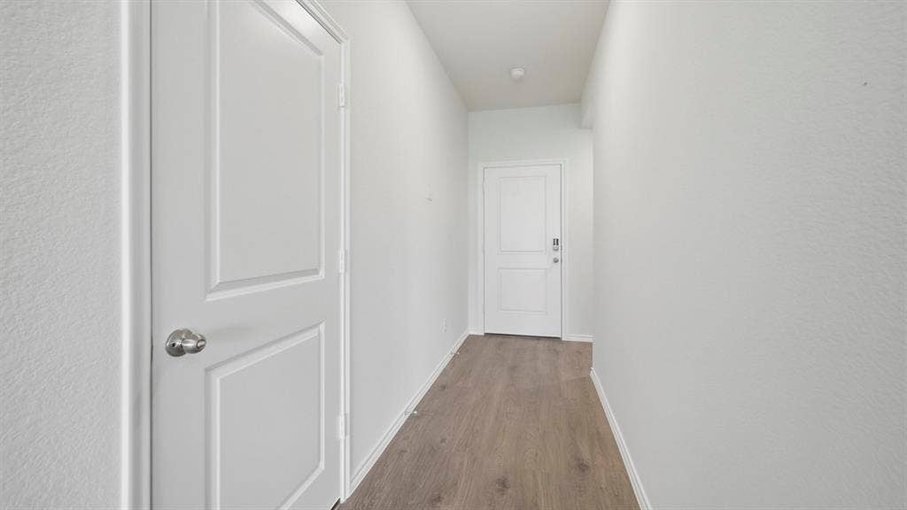 5032 Shumard Drive, Lindale, TX 75771 Hallway featuring wood-finish flooring, white walls, and a two-panel interior door with a chrome knob
