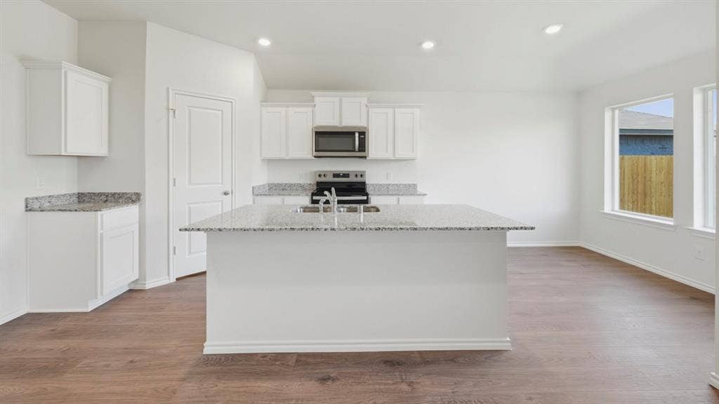 5032 Shumard Drive, Lindale, TX 75771 Central kitchen island with an integrated sink and light-colored speckled countertops