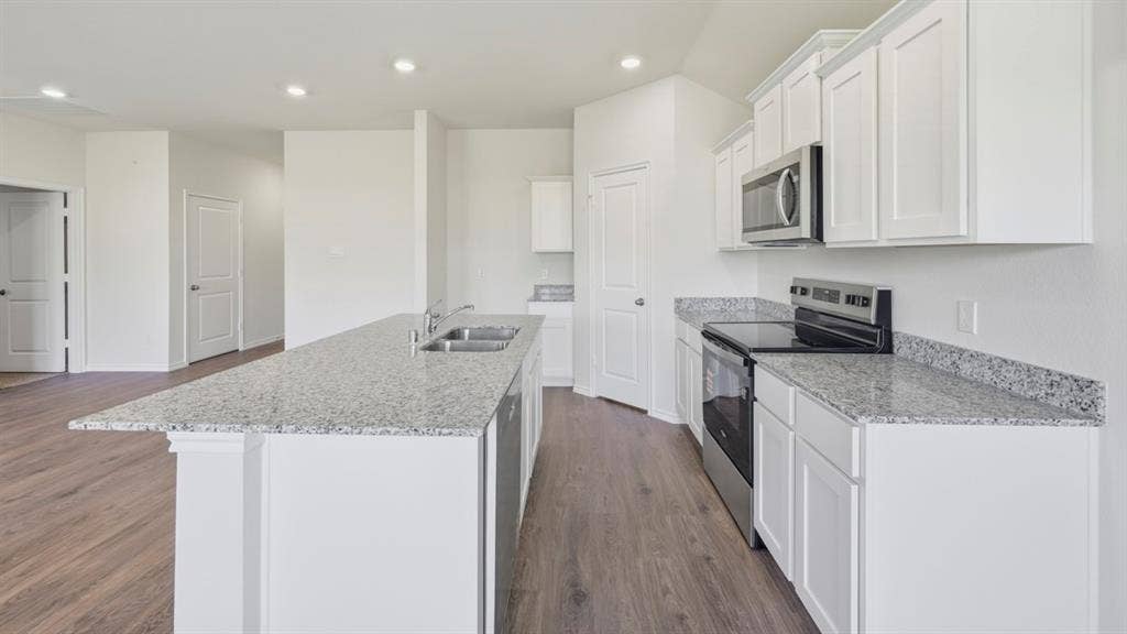 5032 Shumard Drive, Lindale, TX 75771 Kitchen featuring an expansive island with a double basin sink, granite countertops, wood-finish flooring, white cabinetry, and stainless steel appliances