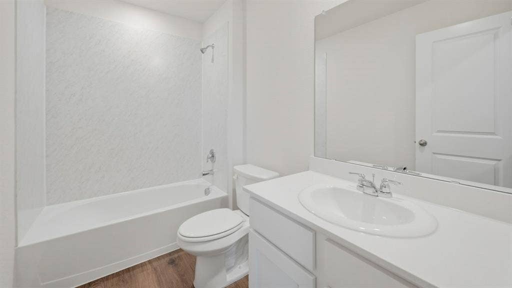 5032 Shumard Drive, Lindale, TX 75771 Full bathroom featuring a white tub-shower combination with textured surround, a white toilet, and a vanity with an integrated sink