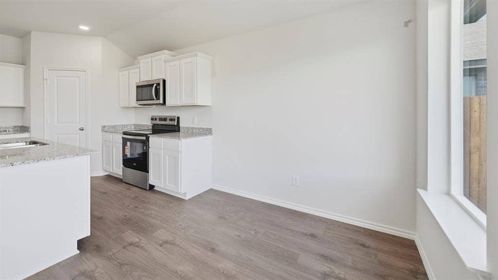 5032 Shumard Drive, Lindale, TX 75771 Kitchen featuring white cabinetry, stainless steel microwave, stainless steel range, and granite-style countertops