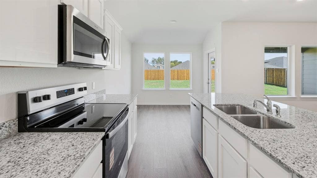 5032 Shumard Drive, Lindale, TX 75771 Bright kitchen featuring white cabinetry, granite countertops, stainless steel appliances, and wood-finish flooring