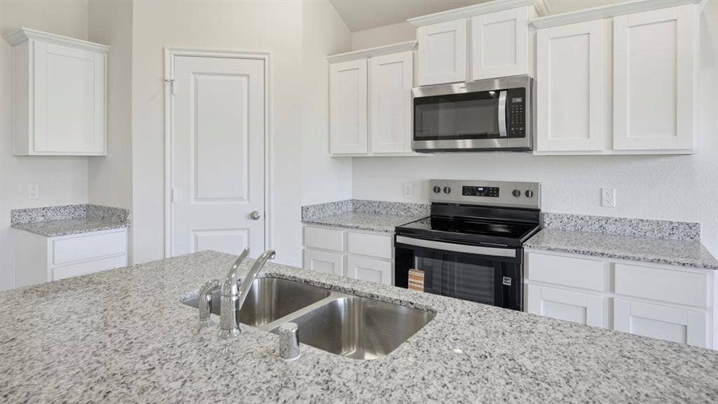 5032 Shumard Drive, Lindale, TX 75771 Kitchen featuring a double basin stainless steel sink, a stainless steel microwave, and an electric range