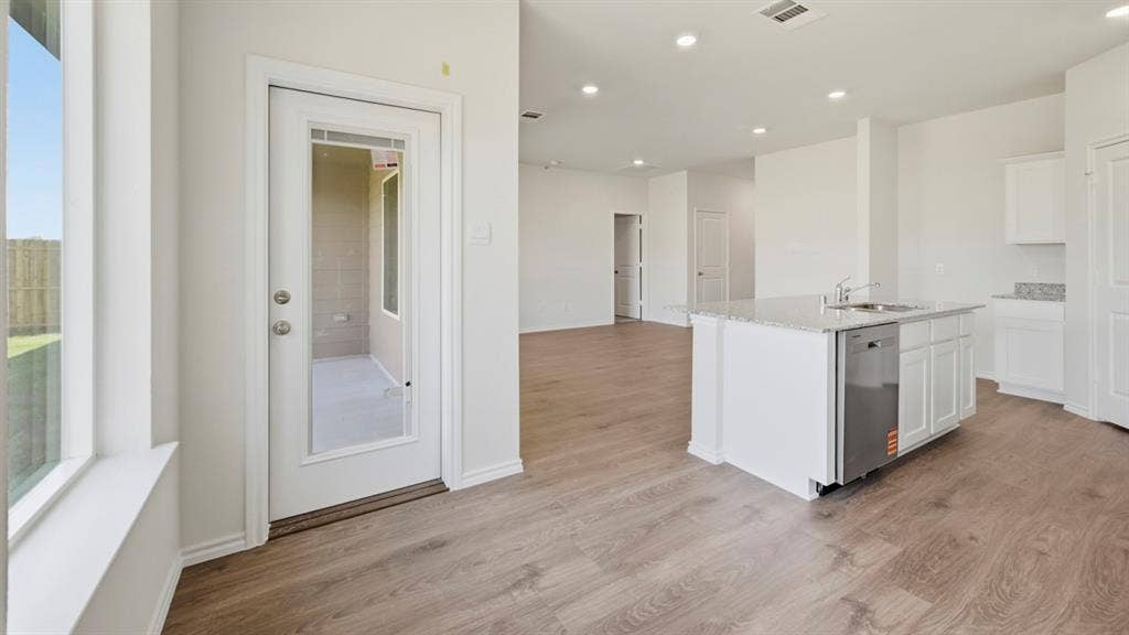 5032 Shumard Drive, Lindale, TX 75771 Open-concept living space featuring wood-finish flooring, recessed lighting, and a kitchen island with an undermount sink and integrated dishwasher