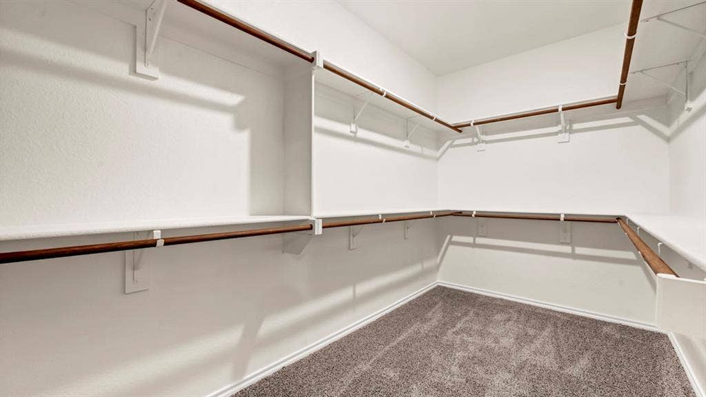 5024 Shumard Drive, Lindale, TX 75706 Walk-in closet featuring extensive built-in shelving and hanging rods, white walls, and gray carpet flooring