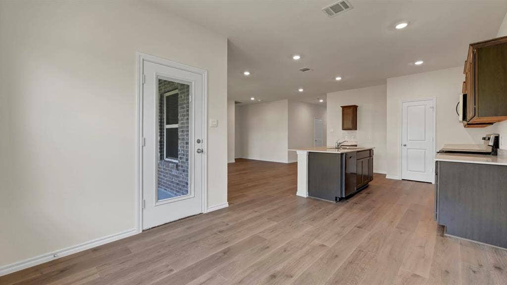 5024 Shumard Drive, Lindale, TX 75706 Open-concept kitchen featuring an island with a sink, wood-finish flooring, recessed lighting, and a glass-paneled exterior door