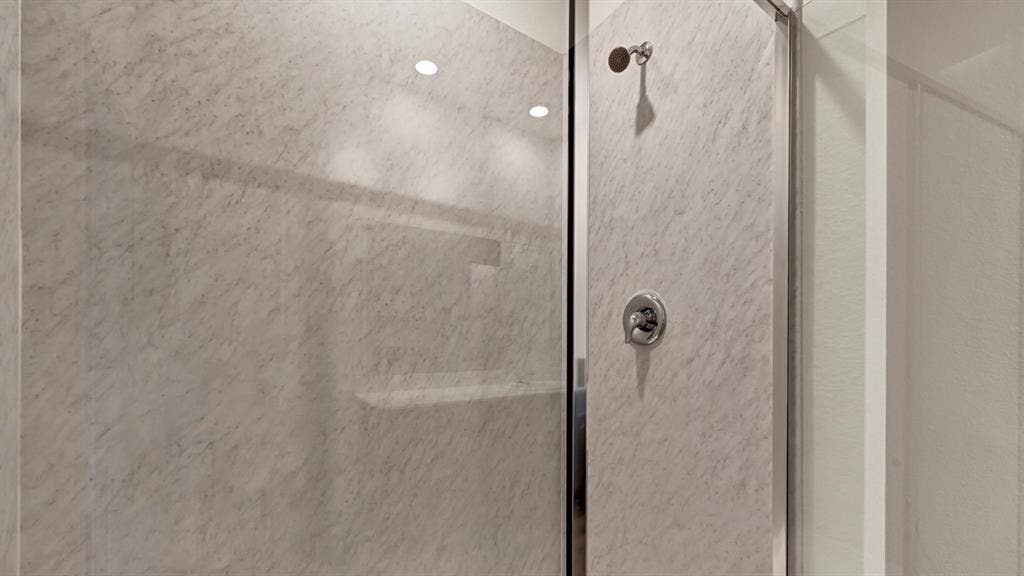 5024 Shumard Drive, Lindale, TX 75706 Shower enclosure featuring a chrome shower head and control, glass panel, and light-toned, textured wall finish