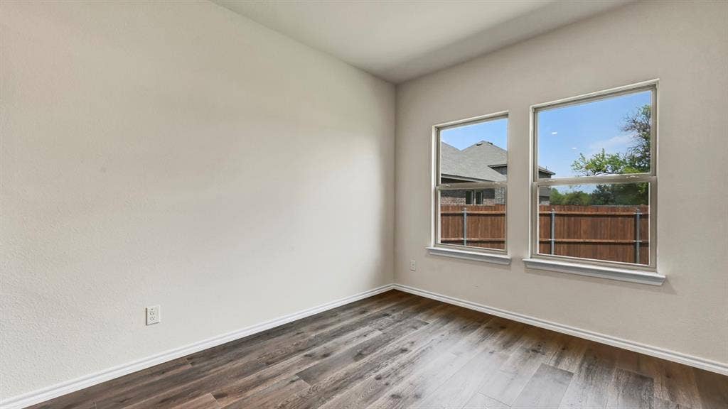 5024 Shumard Drive, Lindale, TX 75706 Bright room featuring two windows, wood-finish flooring, and light-toned walls with white trim