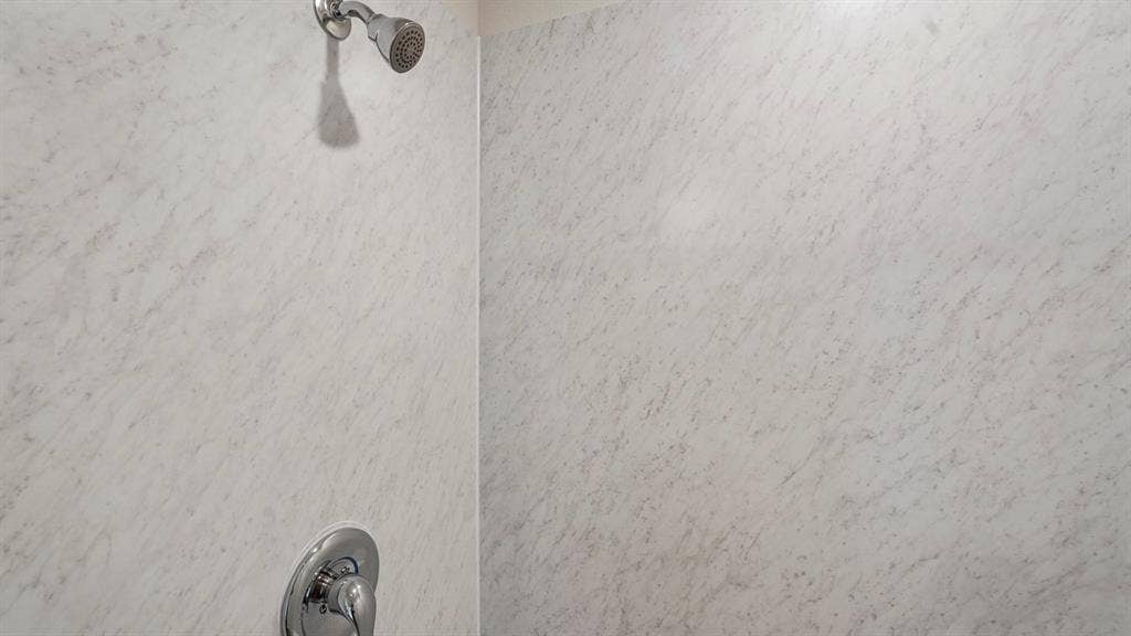 Shower enclosure featuring textured wall panels and polished chrome fixtures