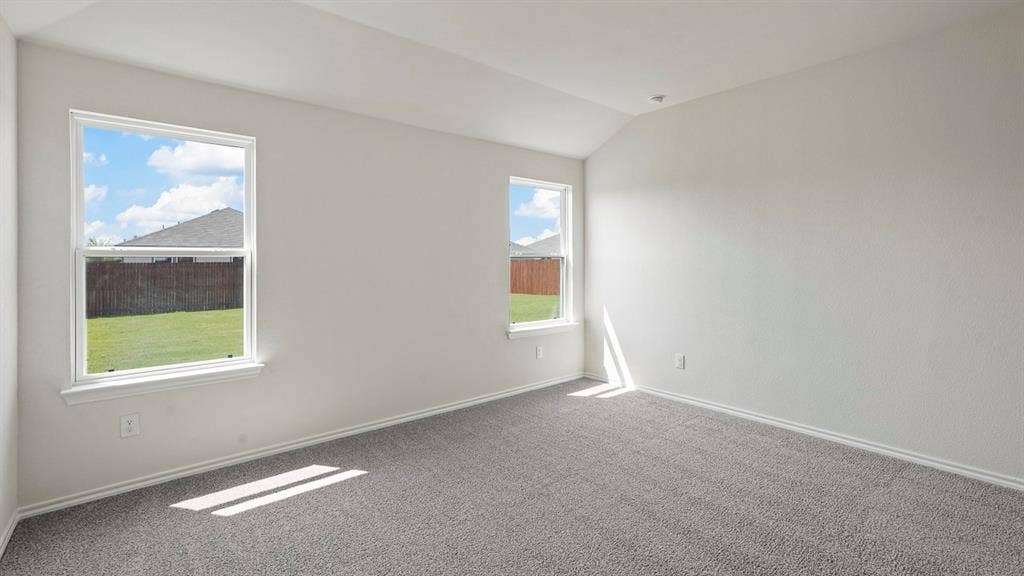 Spacious room featuring vaulted ceilings, light gray wall paint, gray carpet flooring, and two white-framed windows overlooking a green lawn