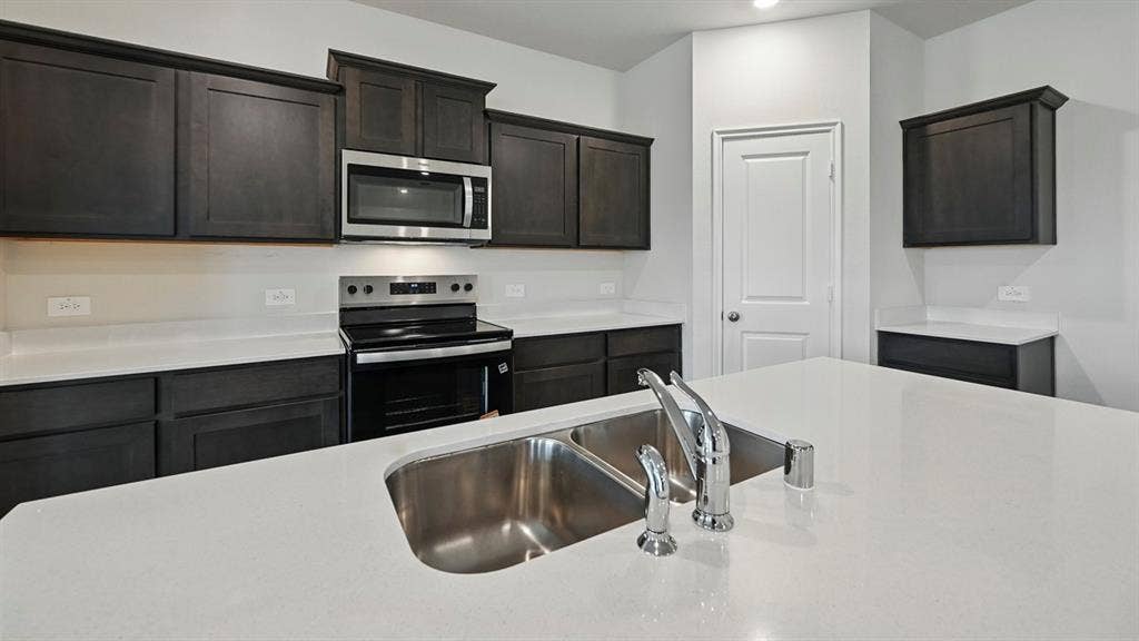 5008 Shumard Drive, Lindale, TX 75771 Kitchen featuring an island with a double basin sink, stainless steel faucet, and white countertops