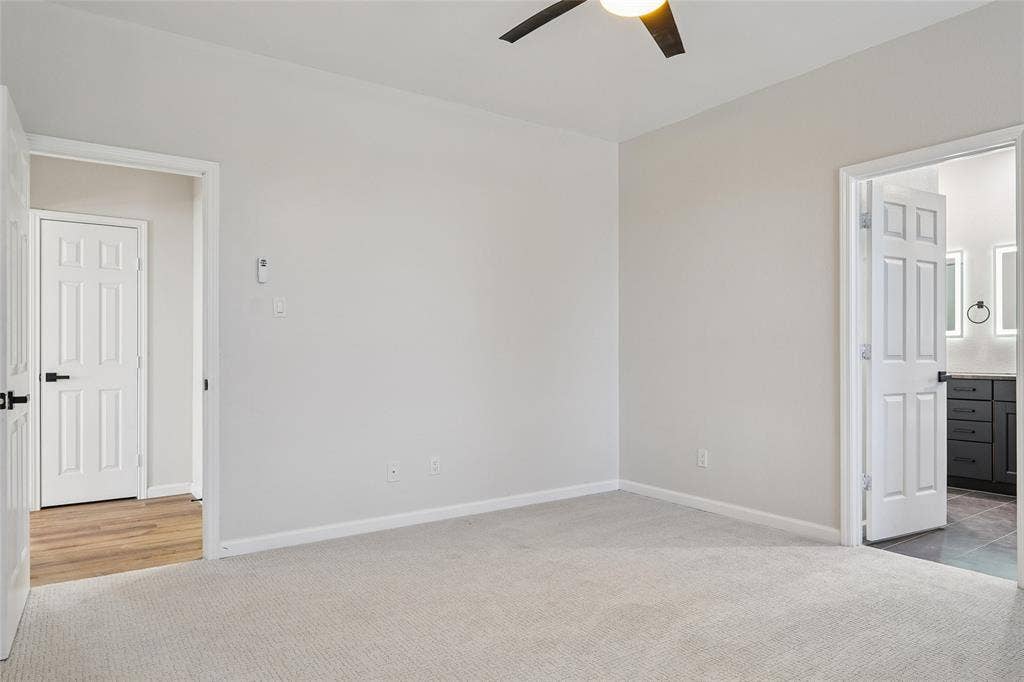 Neutral-toned carpeting, ceiling fan with integrated lighting, paneled interior doors, and modern door hardware