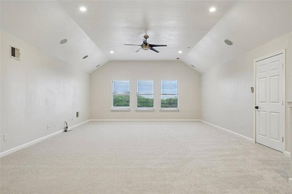Vaulted ceiling with recessed lighting, ceiling fan, carpet flooring, and three windows with blinds