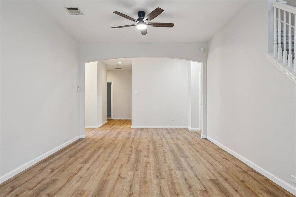 Wood-finish flooring throughout, archway entry, and a ceiling fan