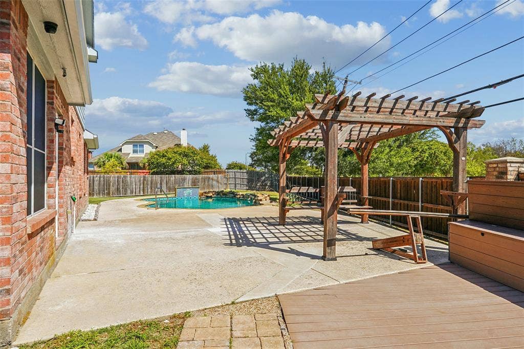 Expansive backyard featuring a swimming pool with a water feature, a wood pergola, composite decking, and a brick exterior