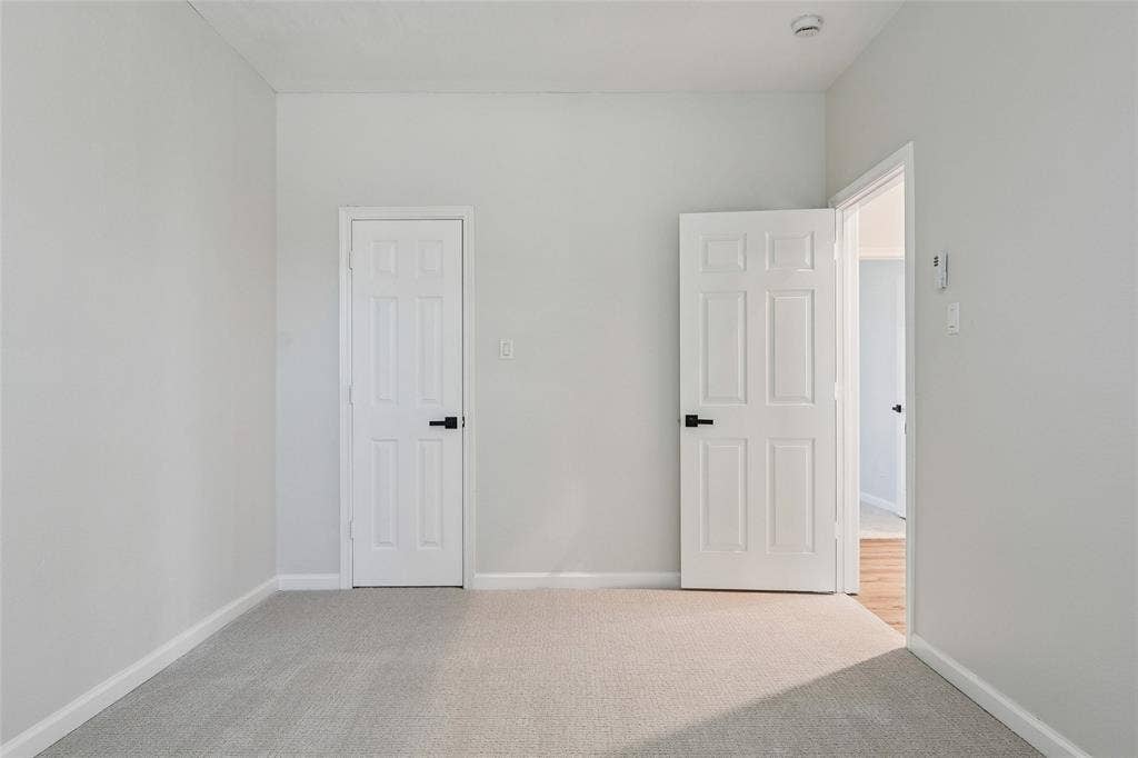 Neutral wall paint, plush carpet, white paneled doors, and black door hardware