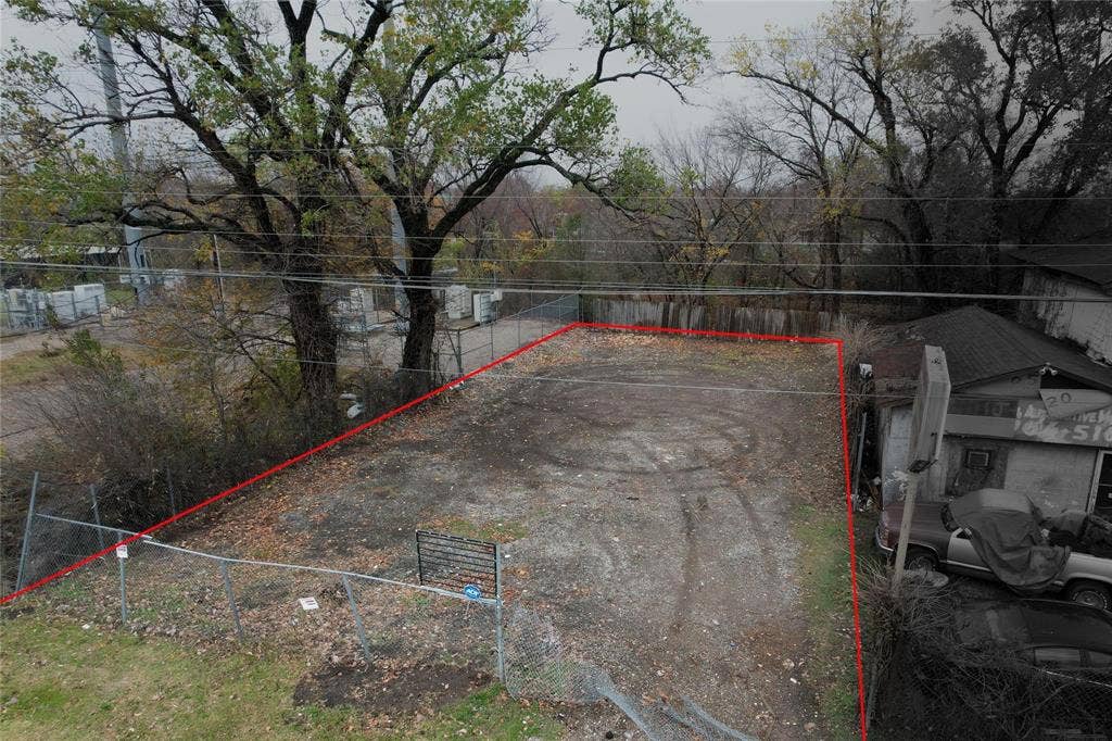 6518 C F Hawn Freeway, Dallas, TX 75217 Fenced lot featuring a gravel surface and mature perimeter trees