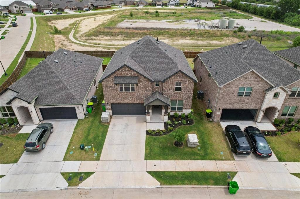 2325 Volans Drive, Haslet, TX 76052 Two-story residence featuring a brick and stone facade, dark shingle roof, and an attached two-car garage. No neighbors behind you!