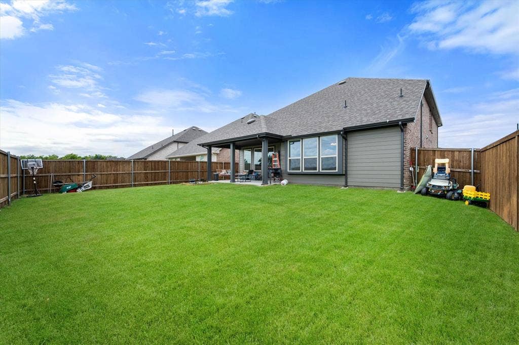 2325 Volans Drive, Haslet, TX 76052 Expansive backyard featuring a lush lawn, privacy fencing, and a covered patio area
