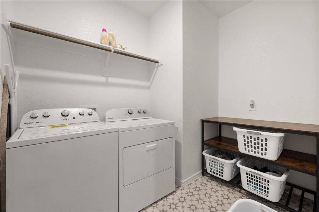 2325 Volans Drive, Haslet, TX 76052 Utility room featuring patterned floor tiles, a built-in shelf with hanging rod, and a freestanding shelving unit with wood-finish tops