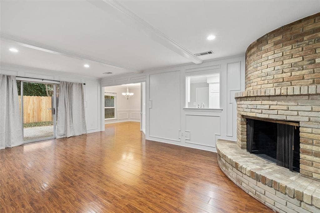 4355 Harvest Hill Road, Dallas, TX 75244 Living room with wood burning fireplace and sliding glass doors that lead out to fenced in side yard and patio.