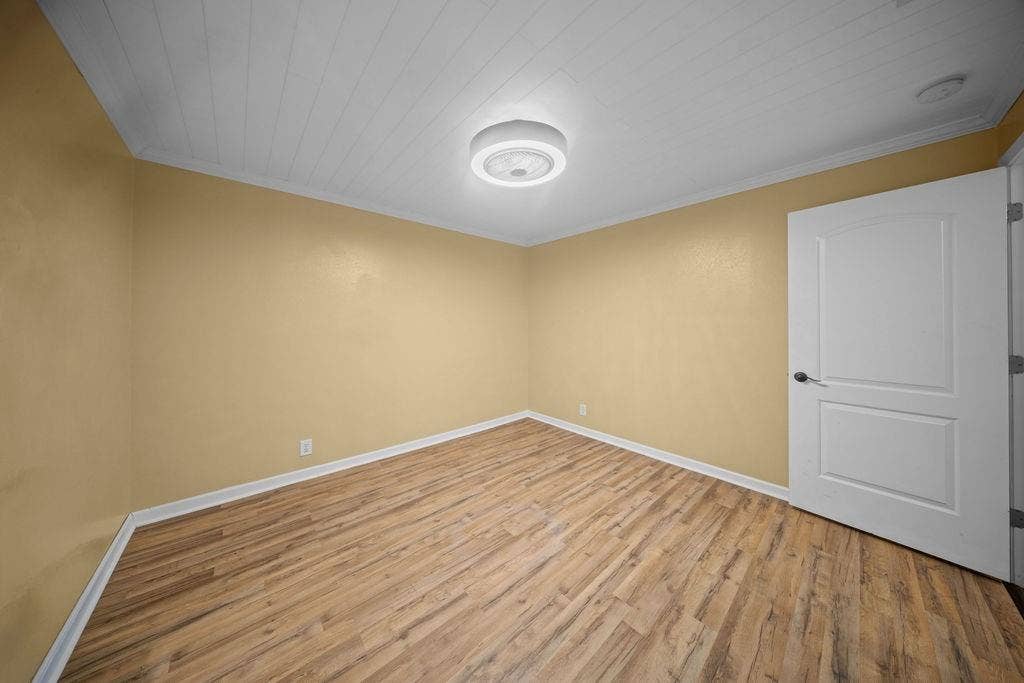 Room featuring wood-finish flooring, light gold walls, and white baseboards