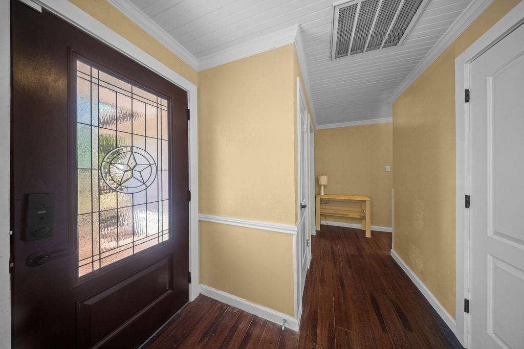 Rich wood-finish flooring complements the detailed leaded glass entry door