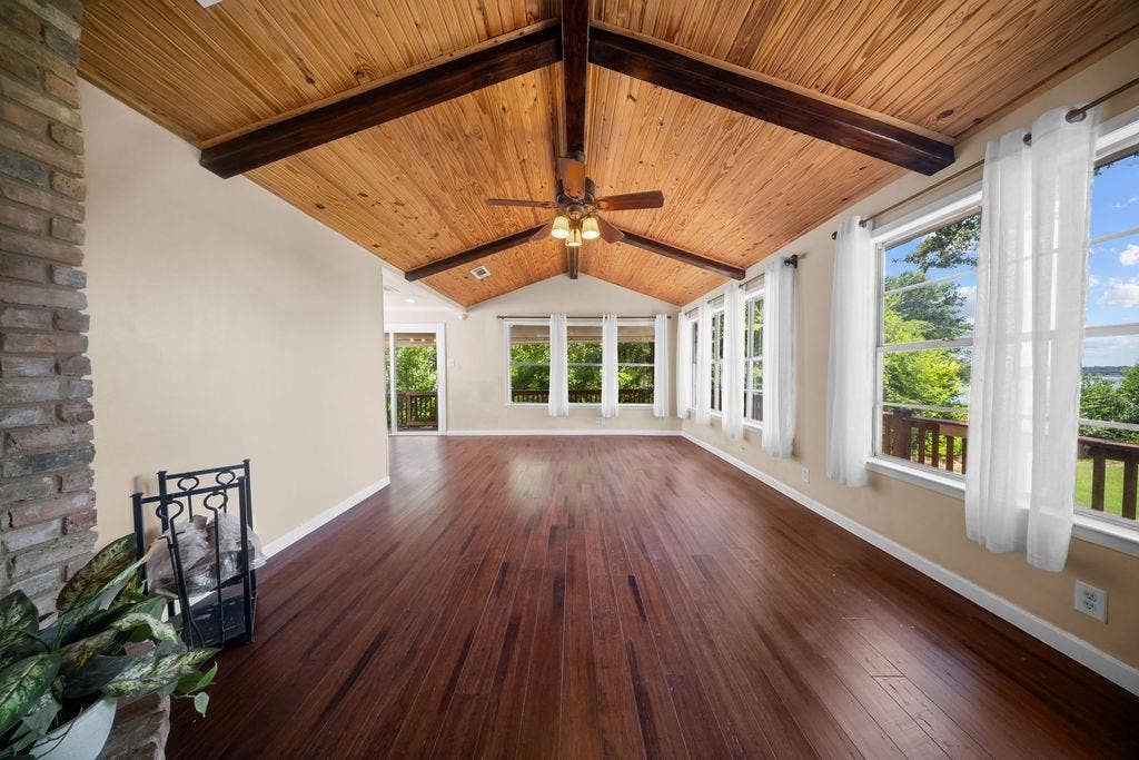 Sunroom featuring wood-finish flooring, a vaulted wood plank ceiling with exposed beams, and a ceiling fan