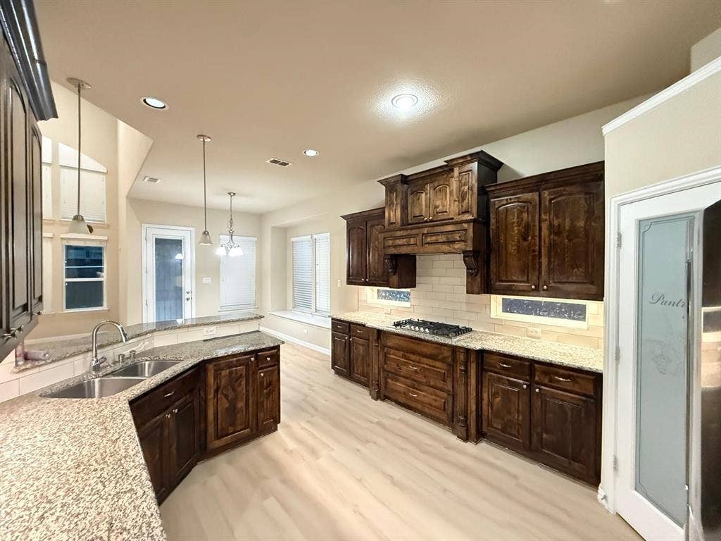 Kitchen featuring dark wood cabinetry, granite countertops, and light wood-finish flooring