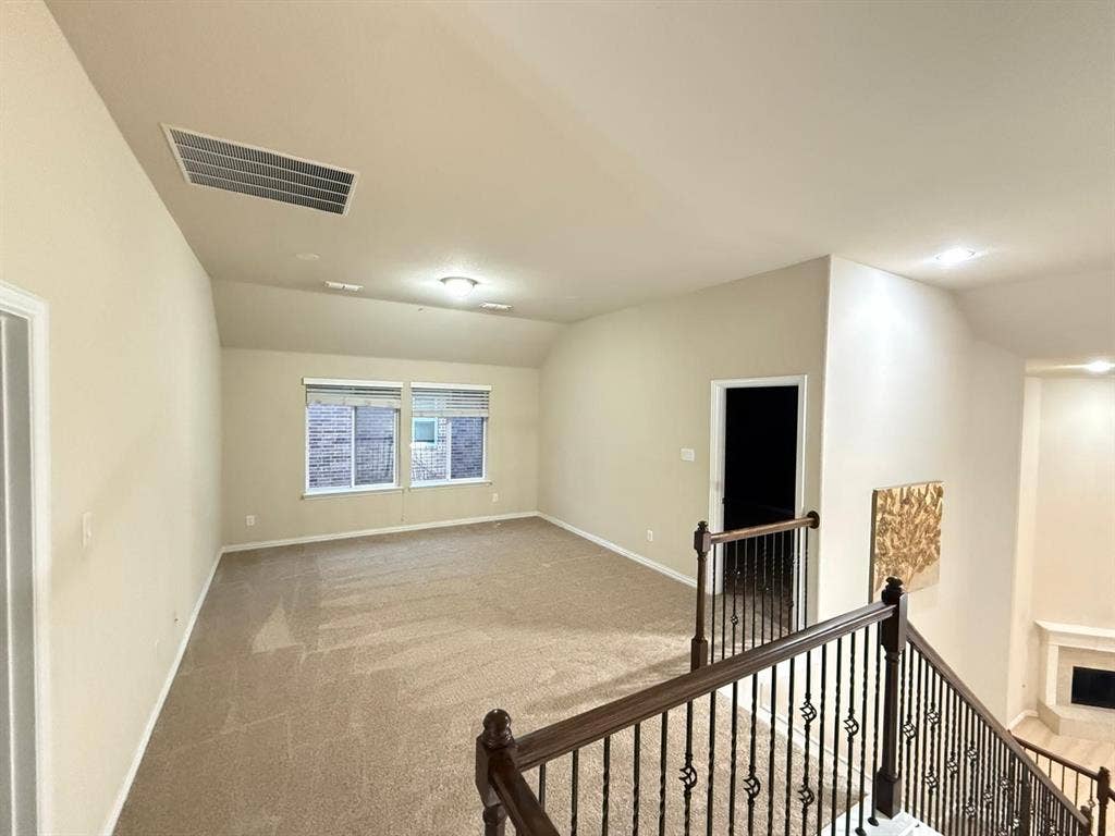 Spacious upper-level room with vaulted ceiling and carpeted flooring