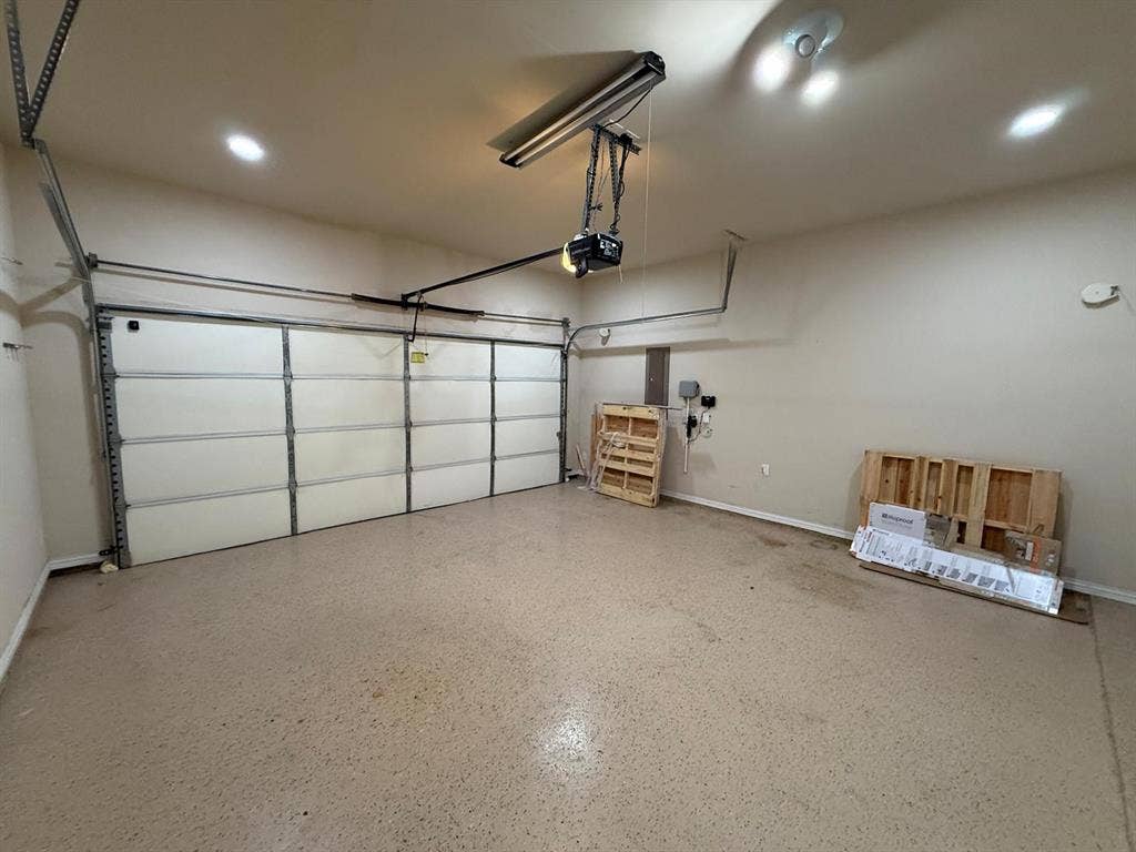 Spacious garage with an epoxy-coated floor, recessed lighting, track lighting, and a garage door opener system