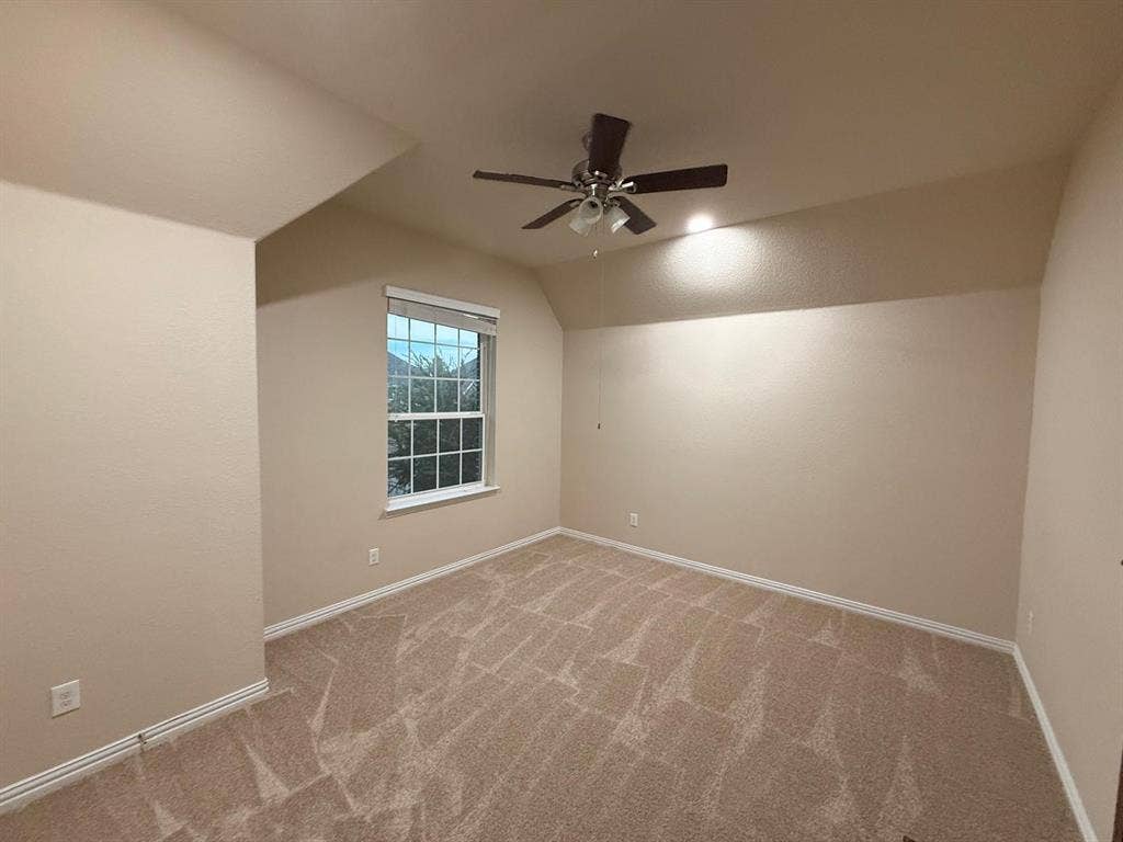 Carpeted room featuring neutral-toned walls, a window with blinds, and an overhead ceiling fan with integrated lighting