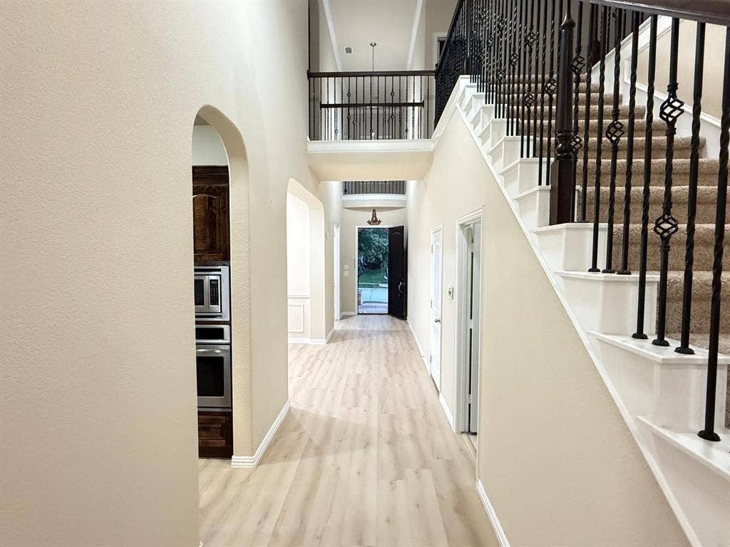 Open foyer with light wood-finish flooring and a two-story ceiling