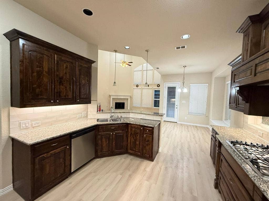 Kitchen featuring dark wood cabinetry, light-toned wood-finish flooring, and light granite countertops