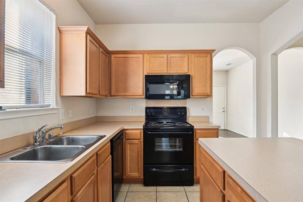 3019 Appaloosa Drive, Dallas, TX 75237 Kitchen featuring sink, light tile patterned floors, and black appliances