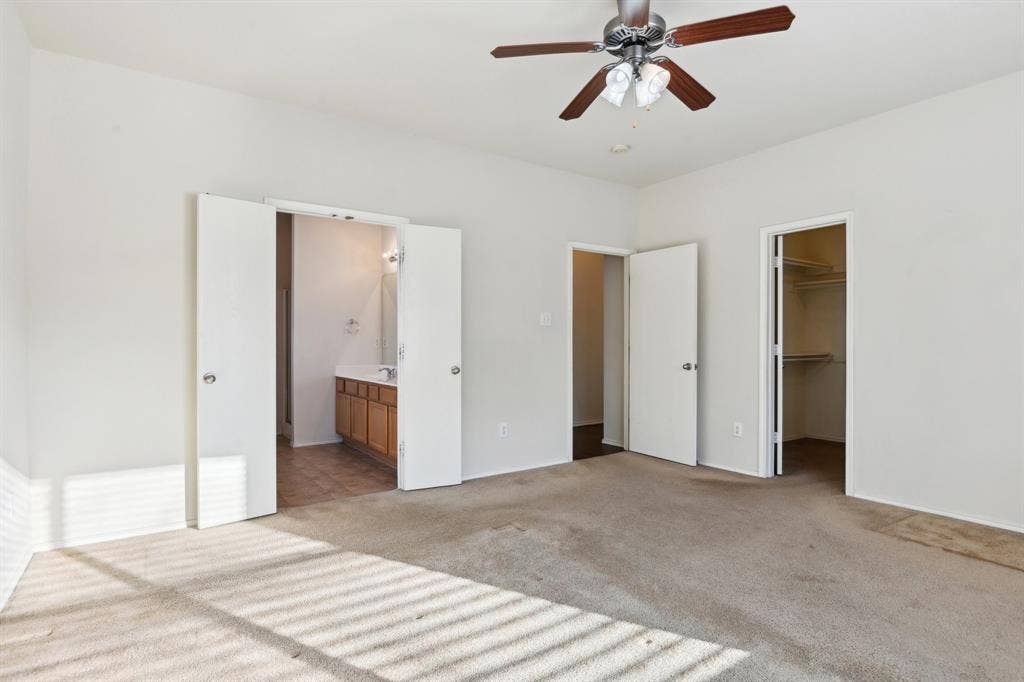 3019 Appaloosa Drive, Dallas, TX 75237 primary bedroom featuring ensuite bath, ceiling fan, light carpet, a walk in closet