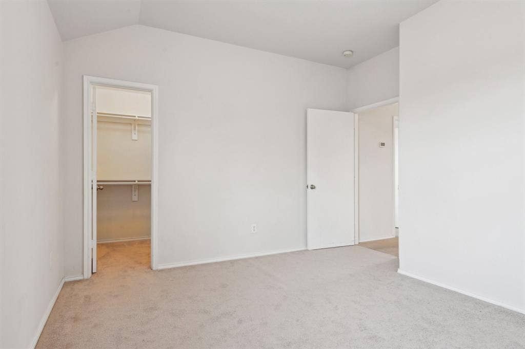 3019 Appaloosa Drive, Dallas, TX 75237 Unfurnished bedroom with vaulted ceiling, a spacious closet, light carpet