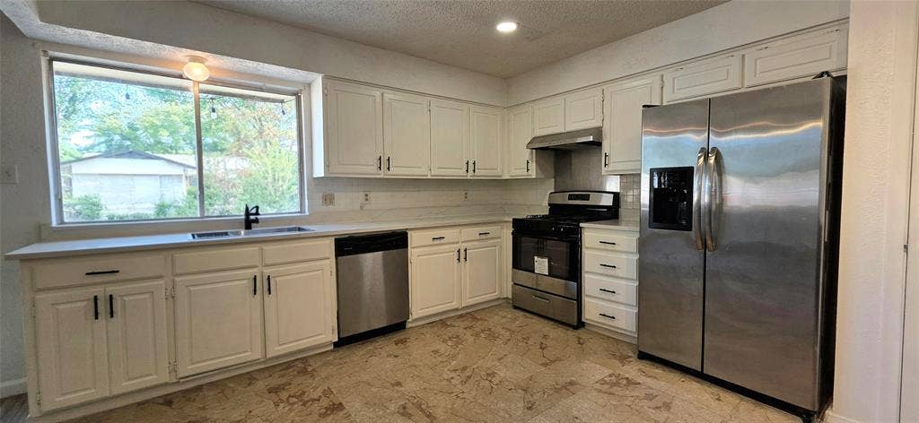 2018 Steamboat Springs Drive, Garland, TX 75044 White cabinetry, stainless steel appliances, stone-look flooring, large window, and recessed lighting