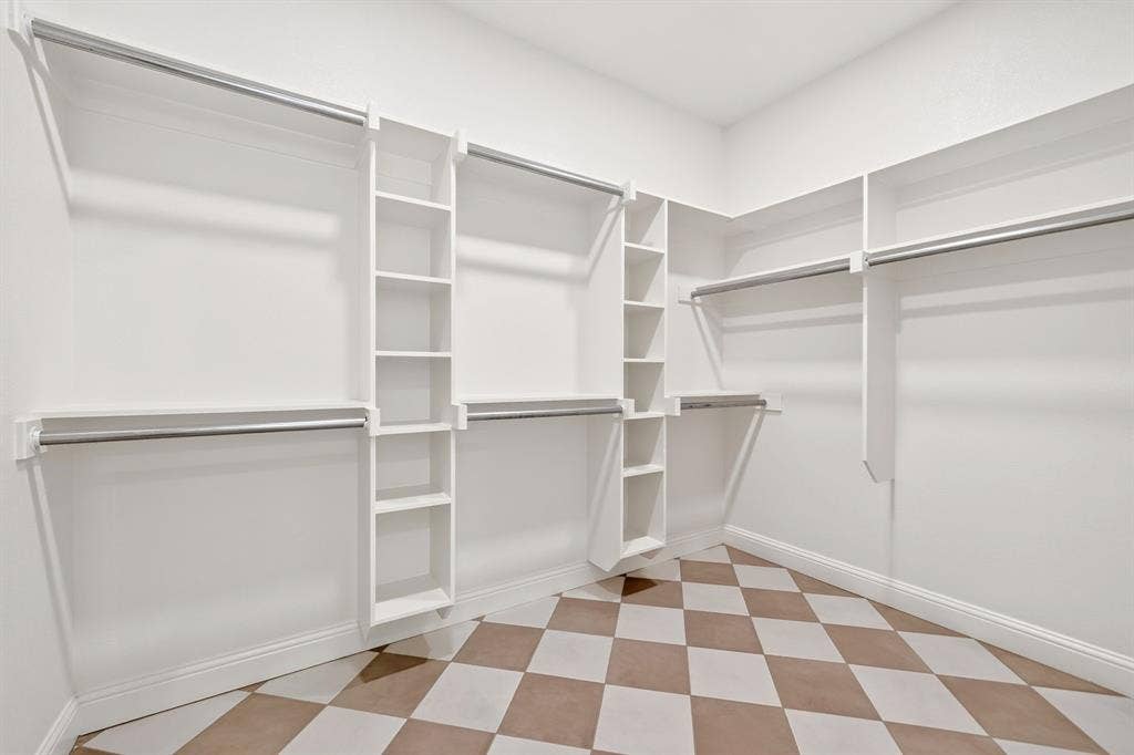 301 Grace Lane, Athens, TX 75751 Expansive walk-in closet featuring white built-in shelving, multiple hanging rods, and a checkered tile floor