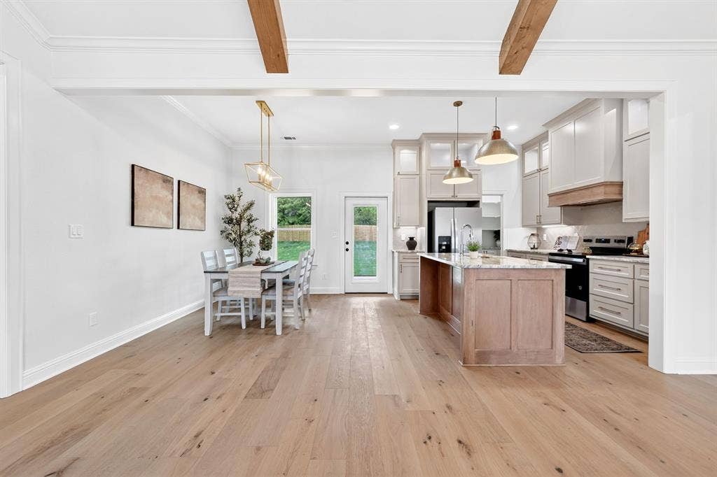 301 Grace Lane, Athens, TX 75751 Open-concept living space featuring wood-finish flooring, exposed ceiling beams, and a dining area with a brass chandelier