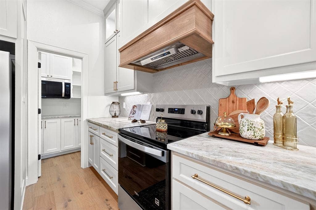 301 Grace Lane, Athens, TX 75751 Modern kitchen featuring white cabinetry, light wood-finish flooring, a stainless steel range, and a wood range hood