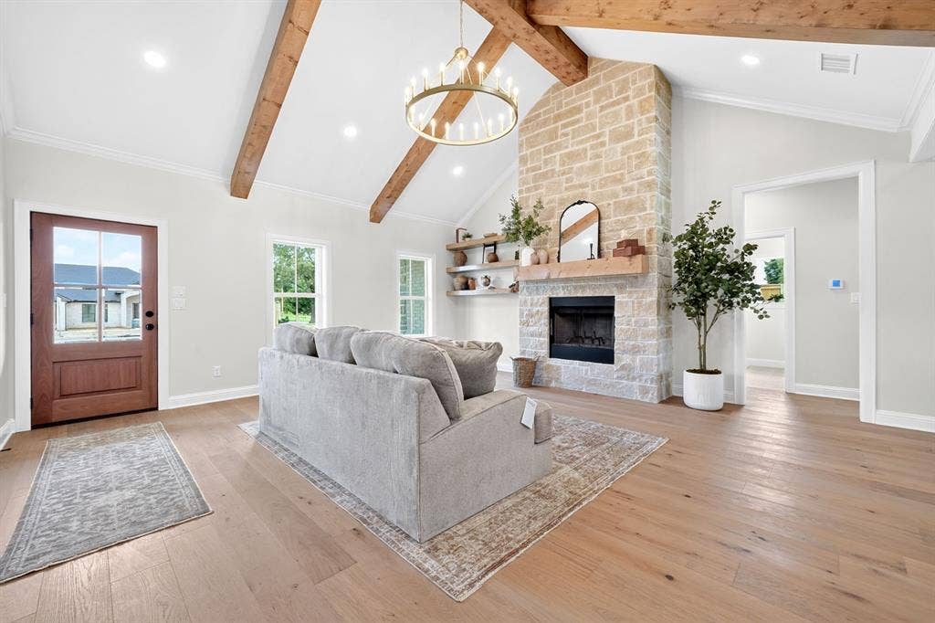301 Grace Lane, Athens, TX 75751 Spacious living area featuring a vaulted ceiling with exposed wood beams, a stone fireplace with a wood mantel, and wood-finish flooring