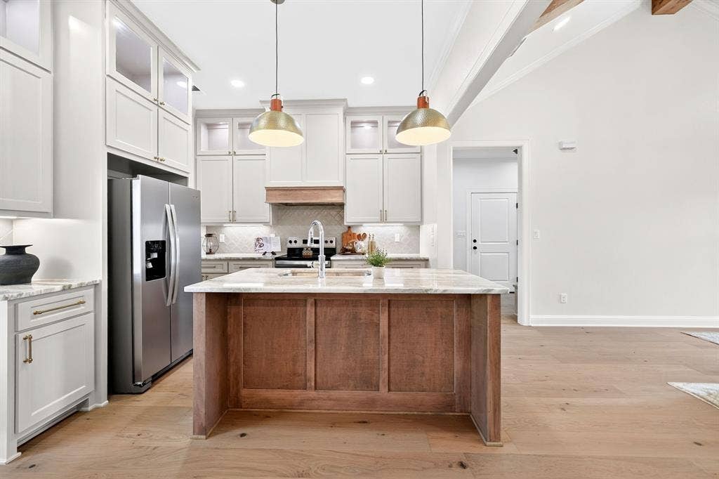 301 Grace Lane, Athens, TX 75751 Kitchen featuring a central island with wood paneling, granite countertops, stainless steel appliances, light cabinetry, and wood-finish flooring