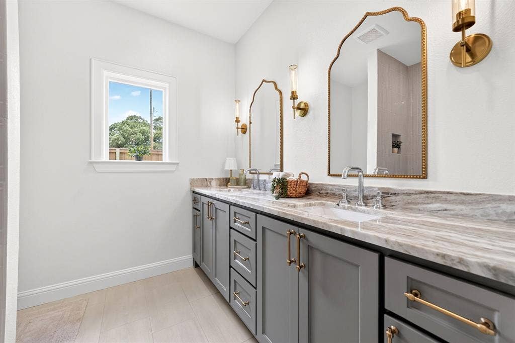 301 Grace Lane, Athens, TX 75751 Dual vanity featuring gray cabinetry, gold-toned hardware, and a stone countertop with integrated sinks