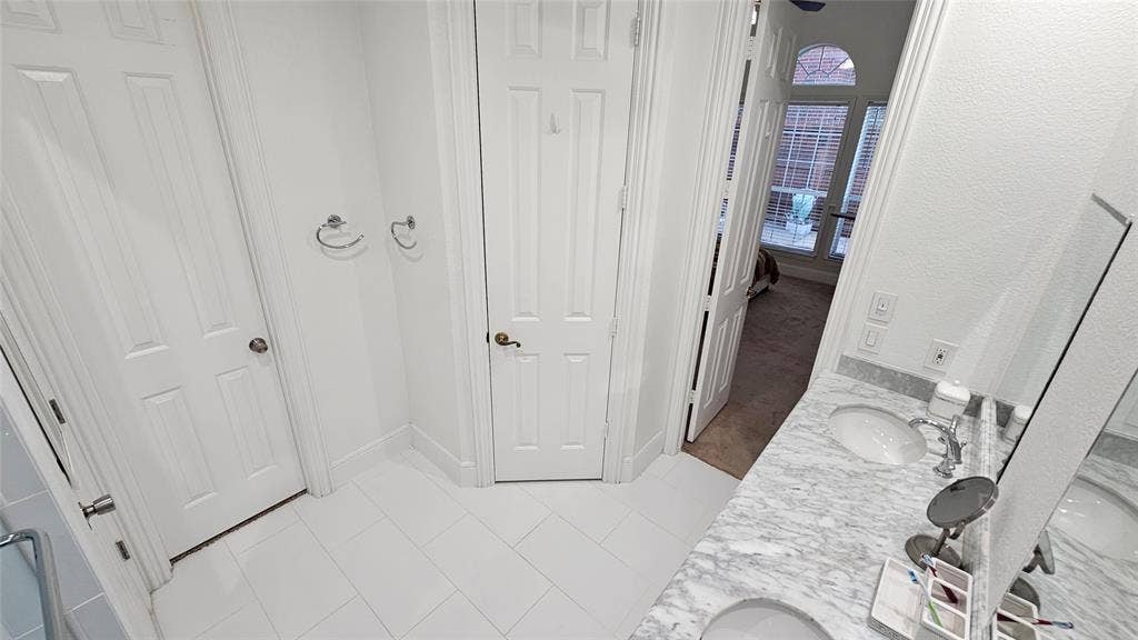Bathroom featuring a double vanity with stone countertops, undermount sinks, and chrome fixtures