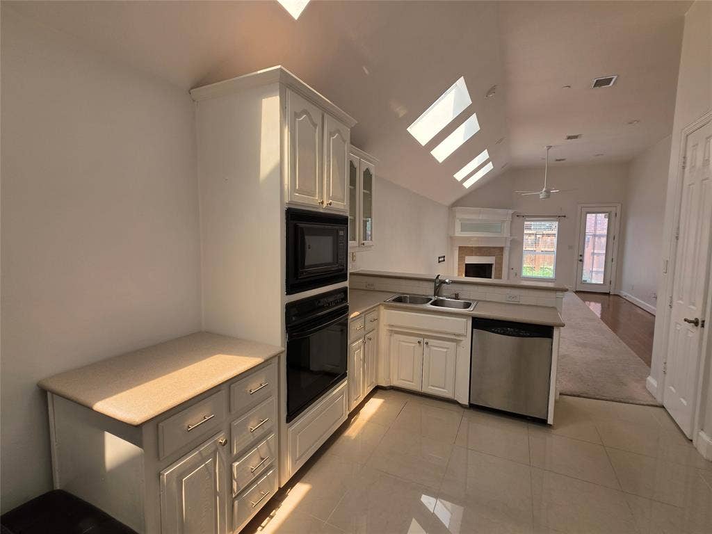 Kitchen featuring white cabinetry, built-in microwave and oven, a stainless steel dishwasher, and a double basin sink