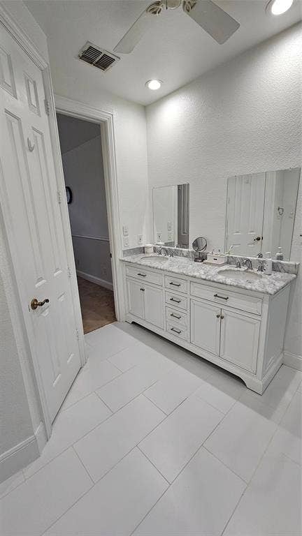 Dual vanity featuring white cabinetry and a light-colored stone countertop with integrated sinks
