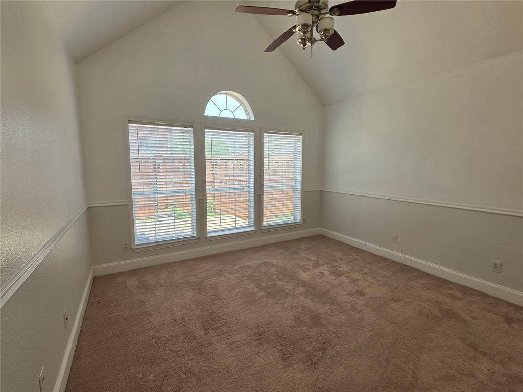 Vaulted ceiling room featuring three large windows with blinds and an arched transom window